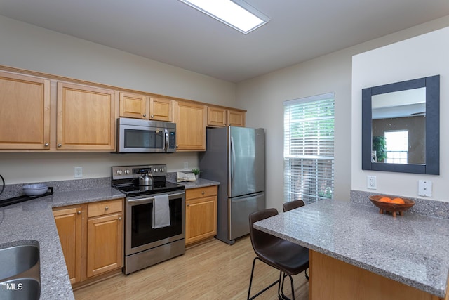 7244 Galon Glen Rd, Raleigh, NC 27613 - kitchen featuring stainless steel appliances, light wood-style flooring, a kitchen breakfast bar, a peninsula, and stone counters