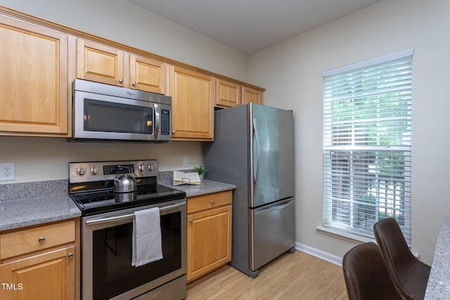 7244 Galon Glen Rd, Raleigh, NC 27613 - kitchen featuring appliances with stainless steel finishes, light wood-type flooring, baseboards, light stone countertops, and light brown cabinetry