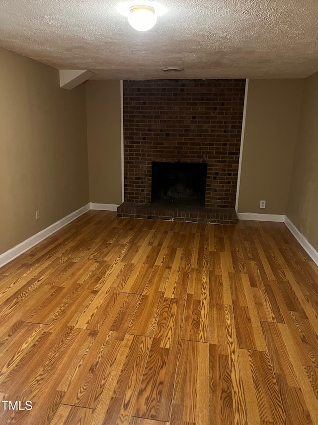 5932 Johnson Pond Rd, Fuquay Varina, NC 27526 - unfurnished living room with a textured ceiling, wood finished floors, and a brick fireplace