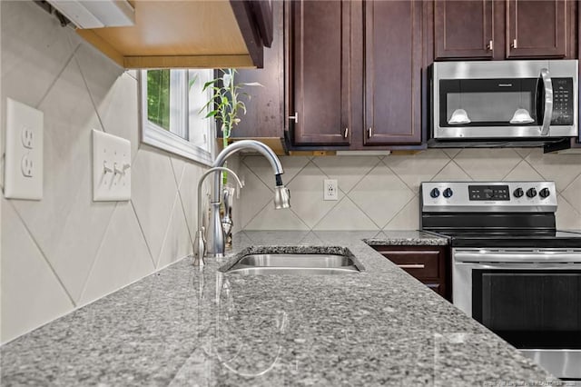 4572 Headwind Dr, Fayetteville, NC 28306 - kitchen with stainless steel appliances, a sink, decorative backsplash, light stone counters, and dark brown cabinets