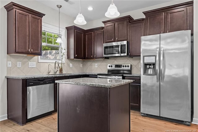 4572 Headwind Dr, Fayetteville, NC 28306 - kitchen with stainless steel appliances, a sink, dark brown cabinets, dark stone countertops, and a center island