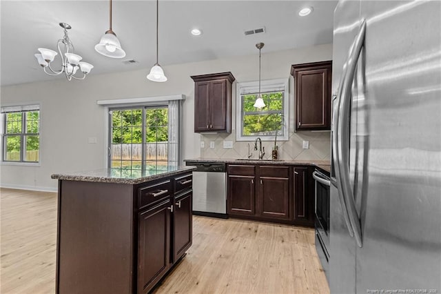 4572 Headwind Dr, Fayetteville, NC 28306 - kitchen featuring stainless steel appliances, a sink, light wood-style flooring, dark stone counters, and a kitchen island