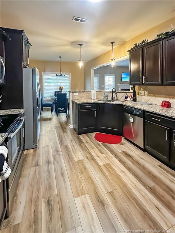 196 Wedgefield Dr, Raeford, NC 28376 - kitchen featuring appliances with stainless steel finishes, a sink, light wood-type flooring, light stone countertops, and a peninsula