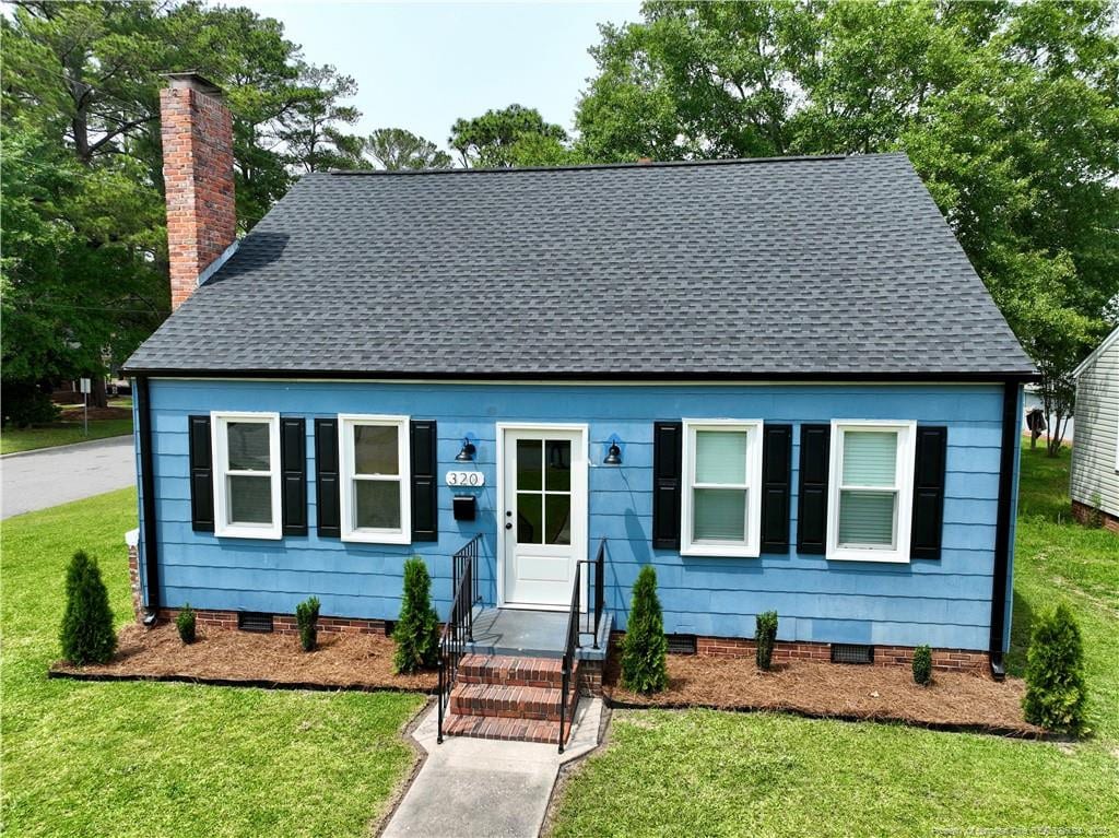 view of front of house with a chimney, a front lawn, a shingled roof, and crawl space