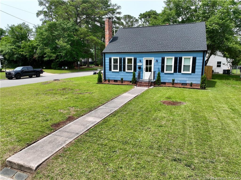 view of front facade featuring crawl space, a chimney, a front yard, and a shingled roof