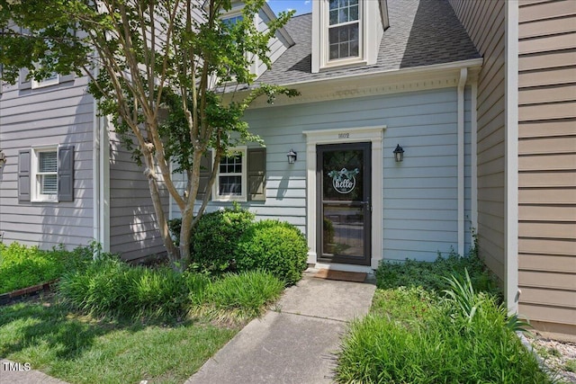 view of exterior entry with a shingled roof