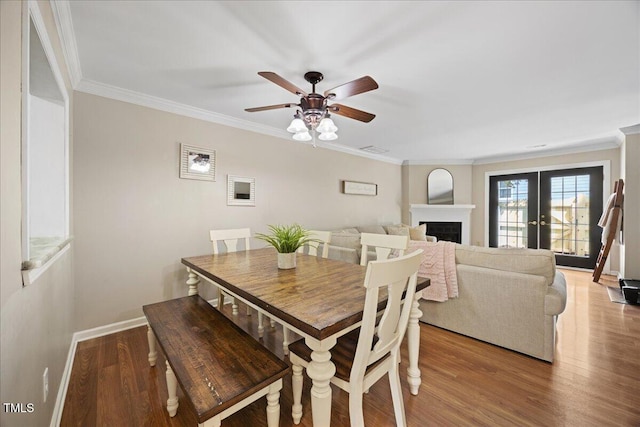 dining space with crown molding, ceiling fan, light wood finished floors, baseboards, and a fireplace