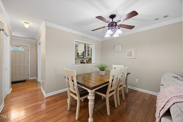 dining room featuring wood finished floors, baseboards, ornamental molding, and ceiling fan