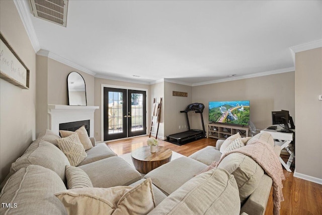 living area featuring french doors, wood finished floors, crown molding, baseboards, and a fireplace