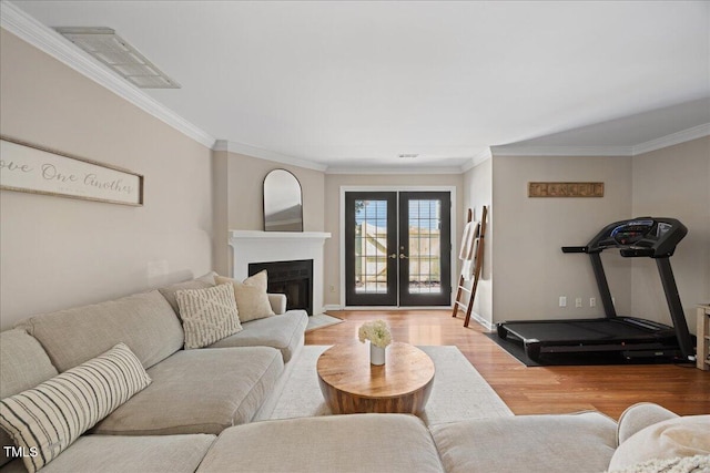 living area featuring wood finished floors, crown molding, french doors, a fireplace with flush hearth, and baseboards