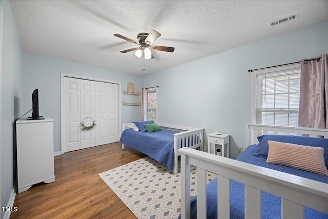 bedroom with wood finished floors, a closet, a textured ceiling, a ceiling fan, and baseboards