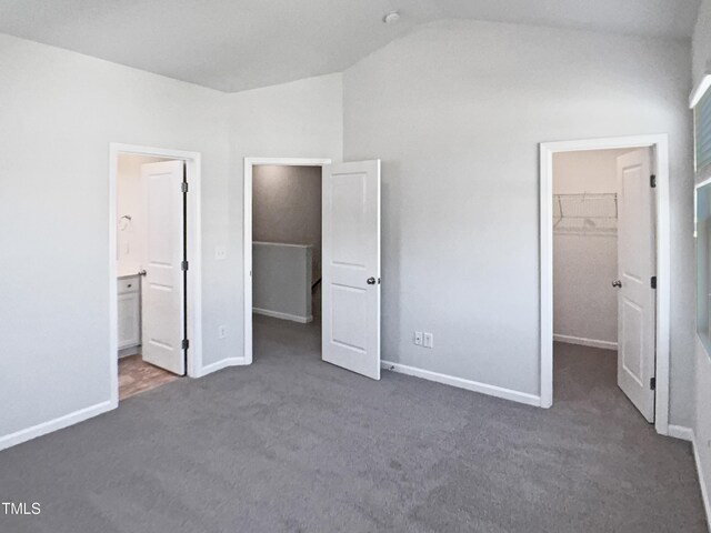 8891 Commons Townes Dr, Raleigh, NC 27616 - unfurnished bedroom featuring a walk in closet, vaulted ceiling, carpet floors, a closet, and baseboards
