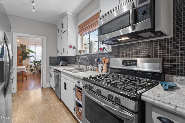 925 S Chestnut St, Henderson, NC 27536 - kitchen with appliances with stainless steel finishes, a sink, light countertops, decorative backsplash, and healthy amount of natural light