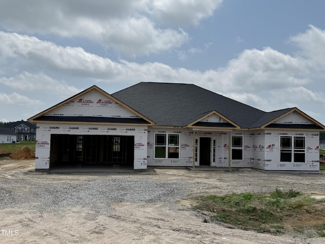 unfinished property featuring an attached garage and gravel driveway