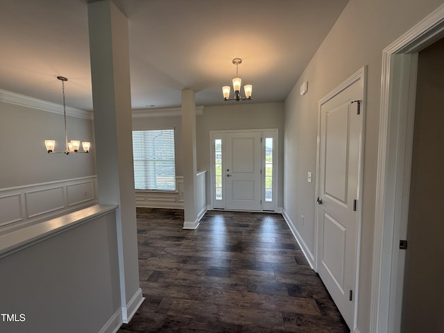 foyer with a chandelier, dark wood-style flooring, ornamental molding, and baseboards