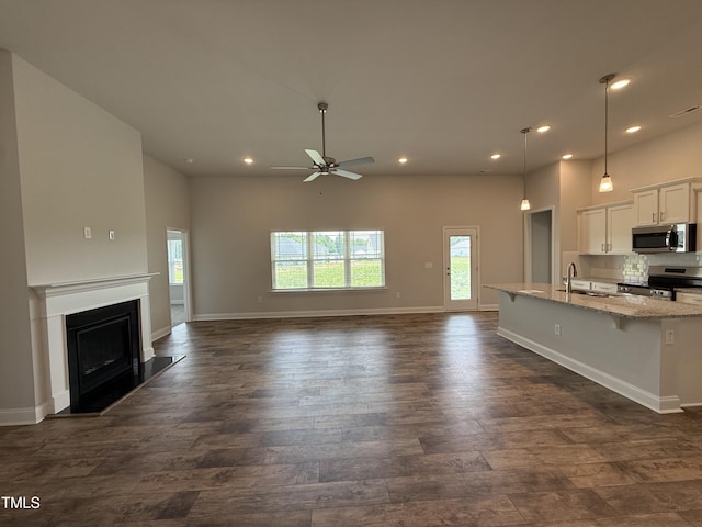 kitchen featuring appliances with stainless steel finishes, a sink, light stone counters, a ceiling fan, and recessed lighting