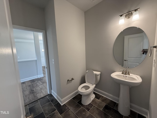bathroom featuring toilet, baseboards, and a sink