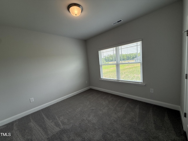 unfurnished room featuring dark carpet and baseboards