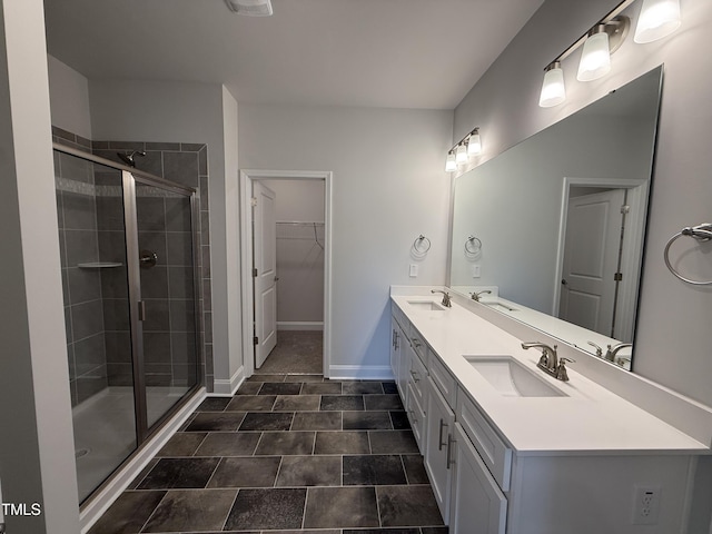 bathroom with a stall shower, double vanity, a walk in closet, and baseboards