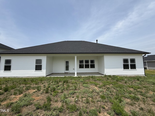 rear view of property with a patio area, a yard, and a shingled roof