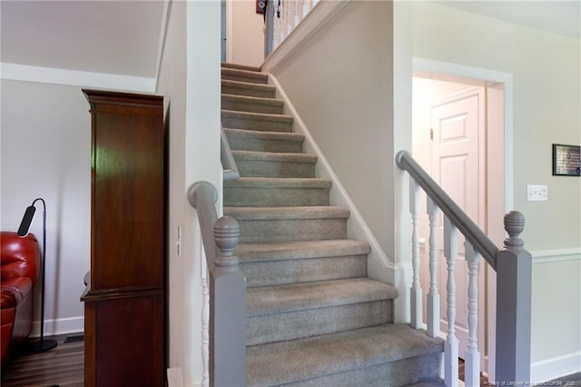 staircase featuring wood finished floors and baseboards