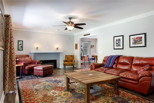 living room with a ceiling fan, a fireplace, wood finished floors, and baseboards