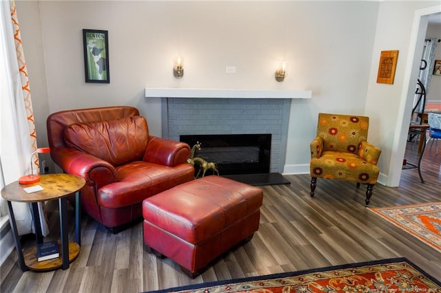 sitting room featuring wood finished floors, a brick fireplace, and baseboards