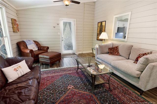 living area with wood finished floors, a ceiling fan, crown molding, and wood walls