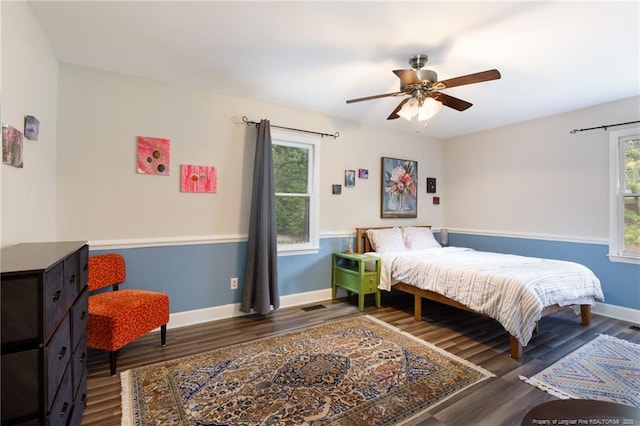 bedroom with multiple windows, wood finished floors, and baseboards