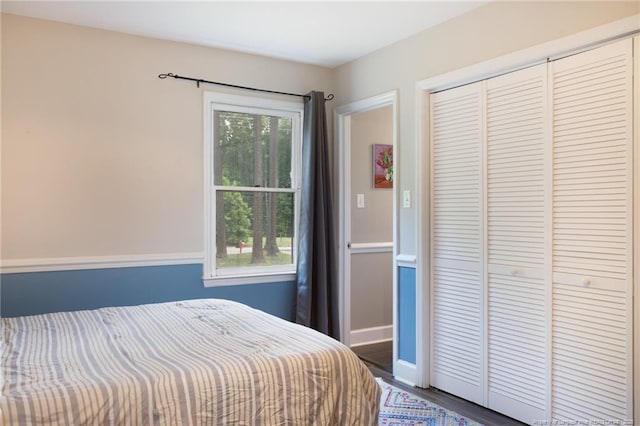 bedroom with a closet, wood finished floors, and baseboards