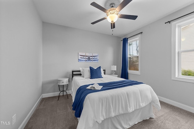 carpeted bedroom featuring baseboards, multiple windows, and a ceiling fan