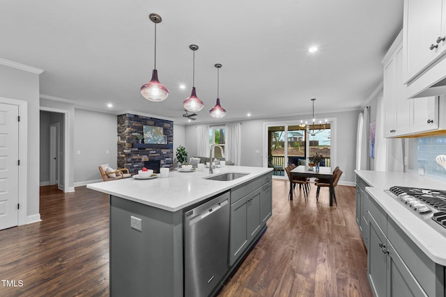 kitchen with a sink, stainless steel appliances, gray cabinets, recessed lighting, and a stone fireplace