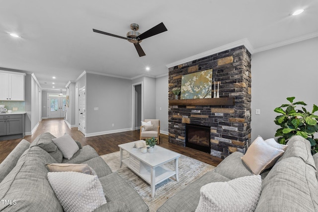 living area with ornamental molding, a stone fireplace, wood finished floors, ceiling fan, and recessed lighting