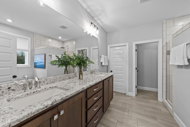 full bath with a stall shower, baseboards, and double vanity