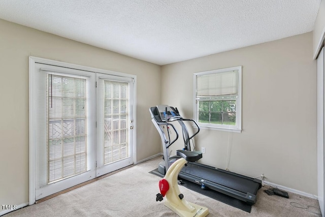 exercise room featuring carpet flooring, a textured ceiling, and baseboards