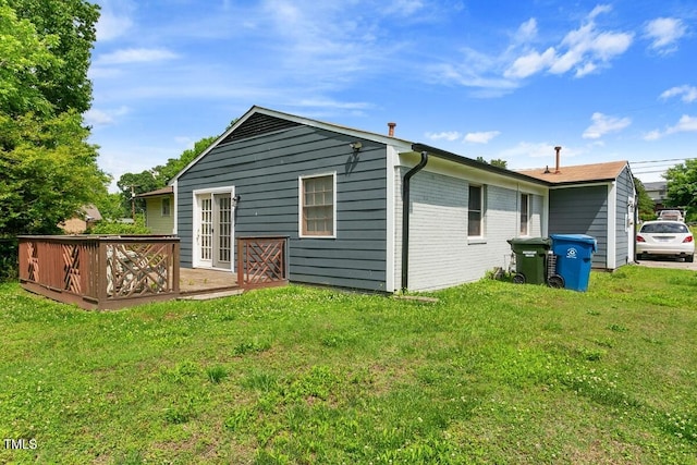rear view of property with a deck, a yard, and brick siding
