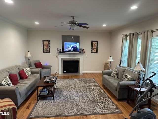 living area with wood finished floors, ceiling fan, recessed lighting, ornamental molding, and baseboards