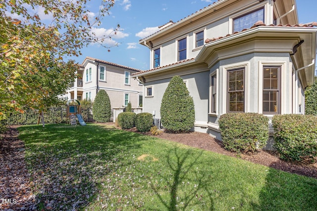 15 Treviso Pl, Durham, NC 27707 - view of side of property featuring stucco siding, a yard, a tile roof, and a playground