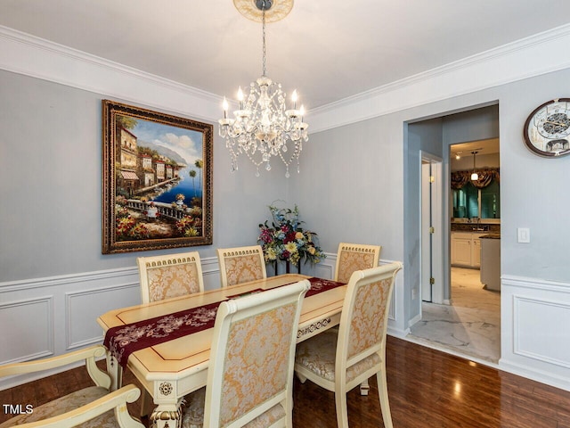 dining area with a chandelier, crown molding, wainscoting, a decorative wall, and wood finished floors
