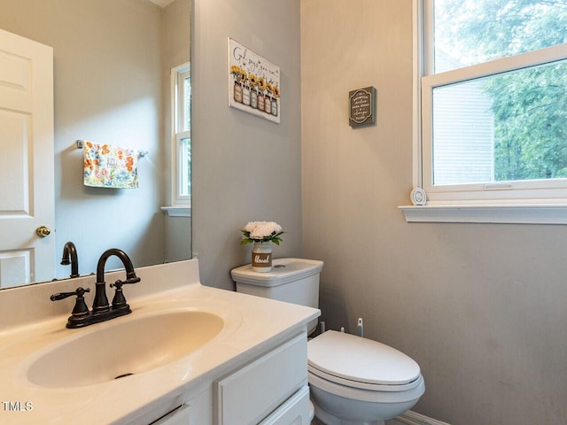 half bath featuring plenty of natural light, toilet, and vanity