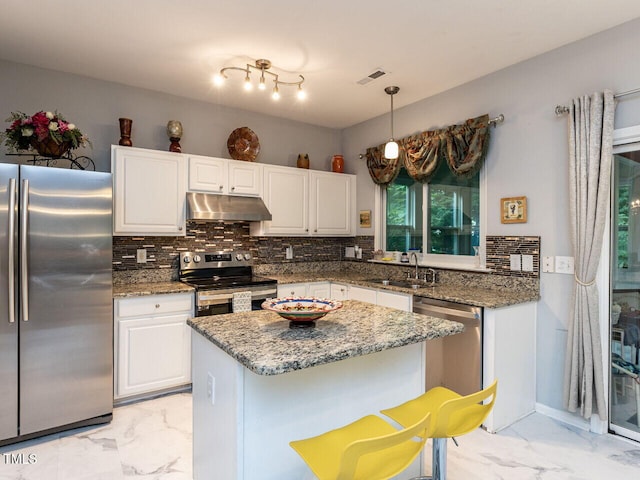 kitchen with stainless steel appliances, under cabinet range hood, light marble finish floors, and a sink
