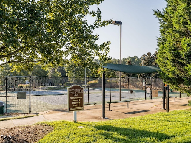 view of community featuring a tennis court and fence