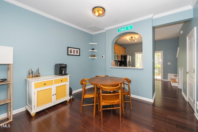 dining room with dark wood finished floors, crown molding, baseboards, and arched walkways