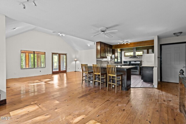 5900 Ebenezer Church Rd, Raleigh, NC 27612 - kitchen with gas stove, track lighting, wall chimney exhaust hood, light wood finished floors, and vaulted ceiling