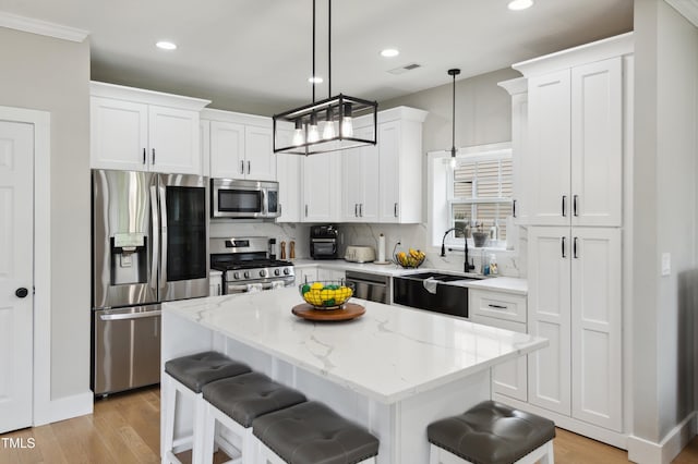 2004 Tennessee Rd, Durham, NC 27704 - kitchen with stainless steel appliances, white cabinets, a breakfast bar area, a center island, and light wood-style floors