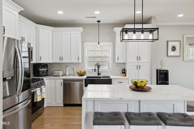 2004 Tennessee Rd, Durham, NC 27704 - kitchen with stainless steel appliances, a sink, backsplash, white cabinetry, and pendant lighting