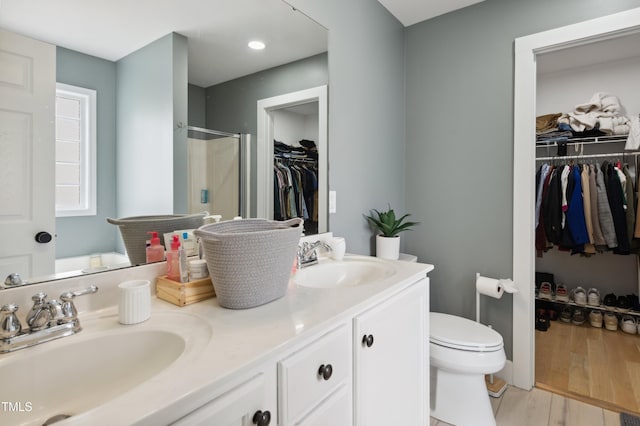 2004 Tennessee Rd, Durham, NC 27704 - bathroom featuring a shower stall, wood finished floors, toilet, double vanity, and a spacious closet