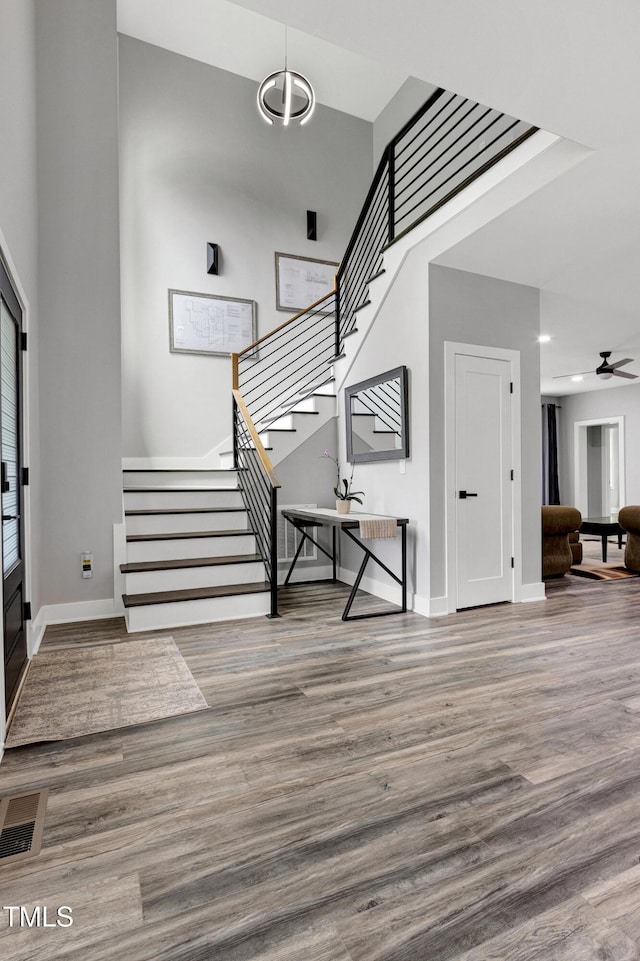 1003 E Sterlington Pl, Apex, NC 27502 - stairs featuring wood finished floors, baseboards, recessed lighting, a ceiling fan, and a towering ceiling