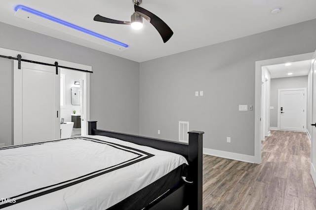 1003 E Sterlington Pl, Apex, NC 27502 - bedroom featuring a barn door, light wood-style flooring, baseboards, ceiling fan, and ensuite bath