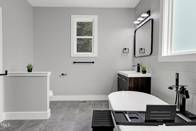 1003 E Sterlington Pl, Apex, NC 27502 - full bathroom featuring a freestanding bath, baseboards, vanity, and toilet